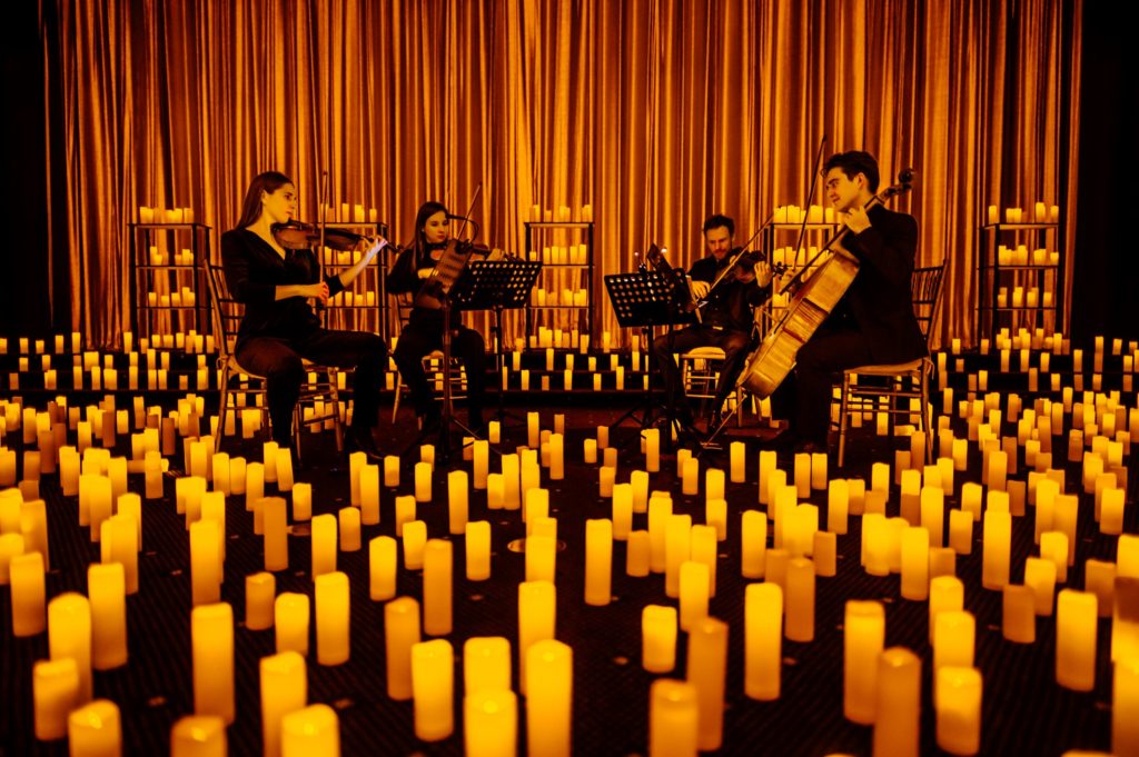 A string quartet surrounded by candles at a Candlight concert.
