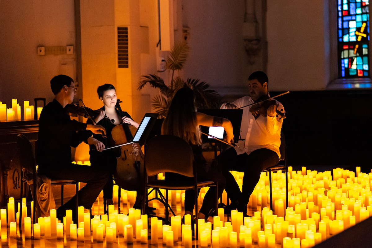A string quartet performing surrounded by candles at a Candlelight concert at St Agnes