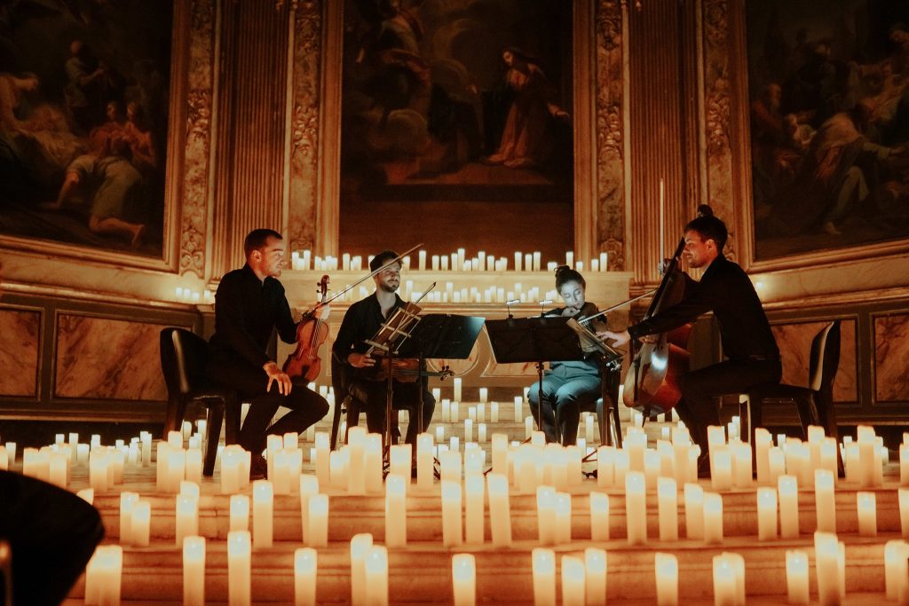 A string quartet performing in an elegant room surrounded by candles at a Candlelight concert.