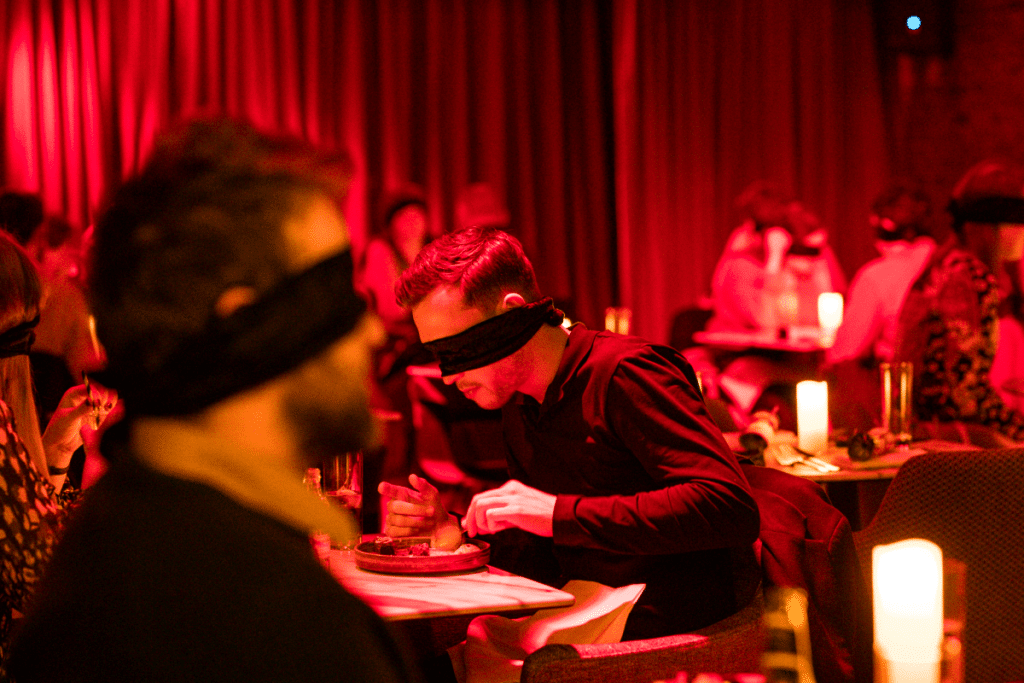 Two men sitting blindfolded at the Dining in the Dark experience.