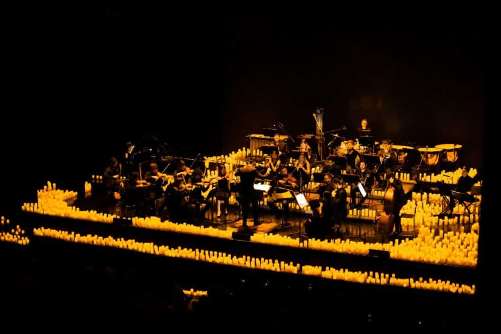 A Candlelight orchestra performing on a stage surrounded by hundreds of candles.
